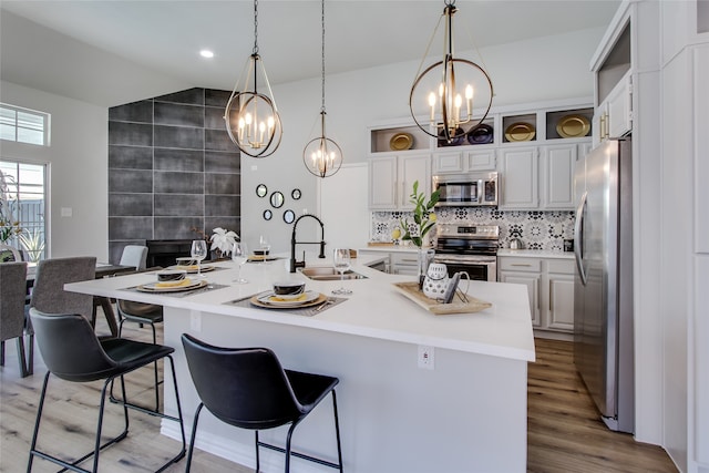 kitchen featuring a breakfast bar area, pendant lighting, stainless steel appliances, and light hardwood / wood-style floors