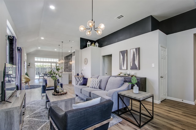 living room with hardwood / wood-style flooring, lofted ceiling, and a chandelier