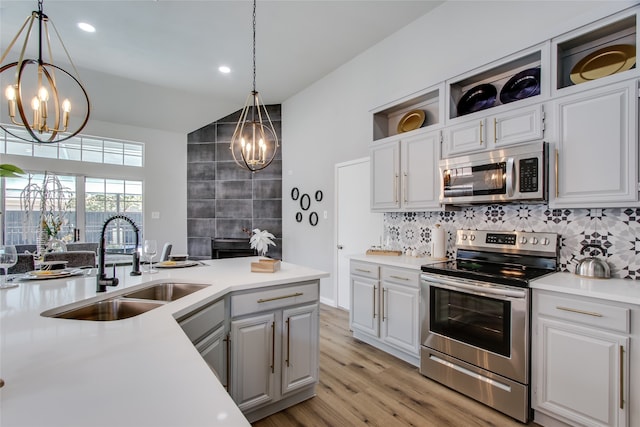 kitchen with sink, hanging light fixtures, light hardwood / wood-style flooring, white cabinetry, and stainless steel appliances