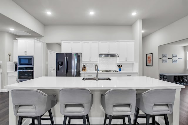 kitchen with a breakfast bar, white cabinets, a large island, dark hardwood / wood-style flooring, and stainless steel appliances