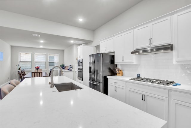 kitchen featuring decorative backsplash, appliances with stainless steel finishes, white cabinetry, and sink