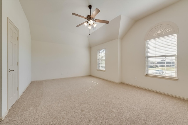 carpeted empty room with ceiling fan, a healthy amount of sunlight, and vaulted ceiling