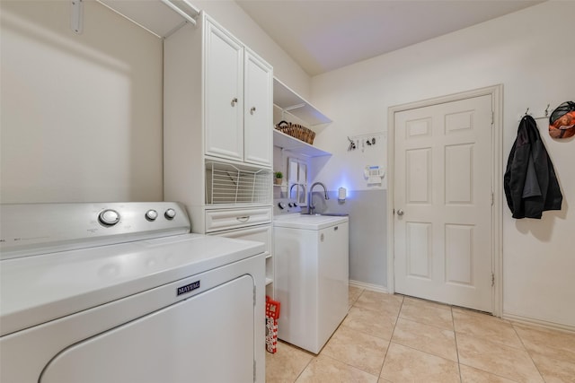 clothes washing area featuring light tile patterned flooring, cabinets, and independent washer and dryer