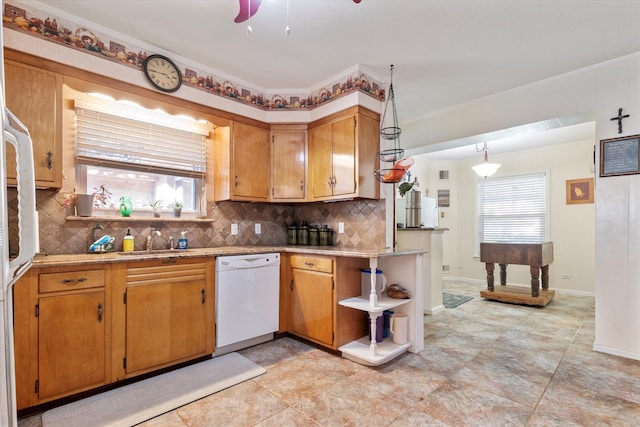 kitchen featuring backsplash, white dishwasher, crown molding, and a healthy amount of sunlight