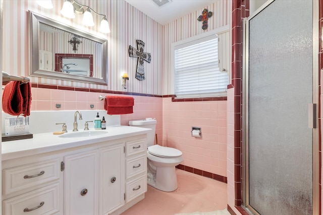 bathroom featuring vanity, a shower with shower door, tile walls, and toilet