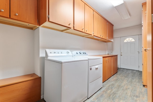 clothes washing area featuring separate washer and dryer, cabinets, and light wood-type flooring