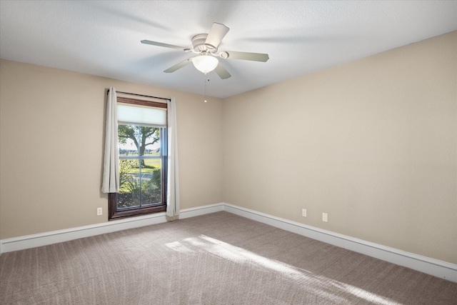 carpeted empty room with a ceiling fan and baseboards