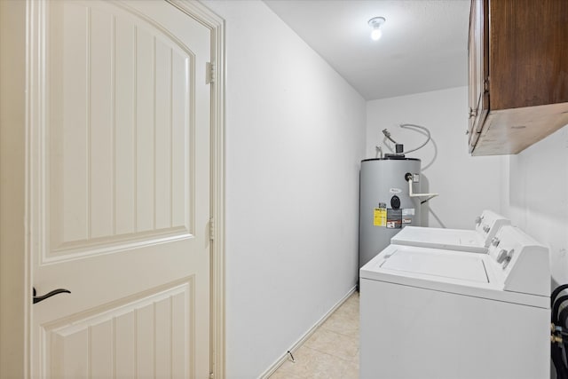 clothes washing area with water heater, cabinets, light tile patterned flooring, and washing machine and clothes dryer