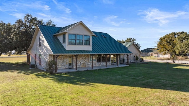 back of property featuring central AC unit, a standing seam roof, stone siding, a lawn, and metal roof