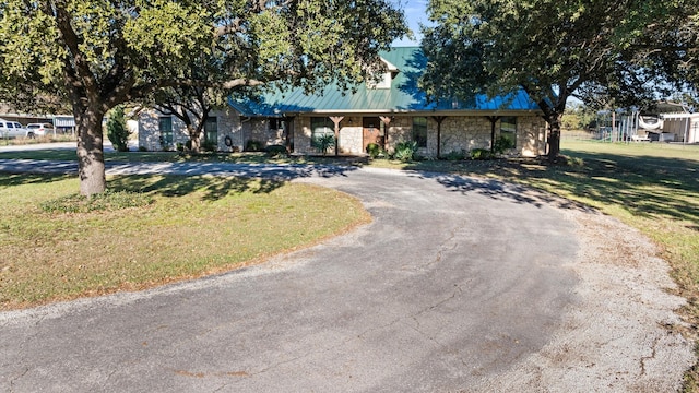 view of front of home with stone siding, driveway, and a front yard