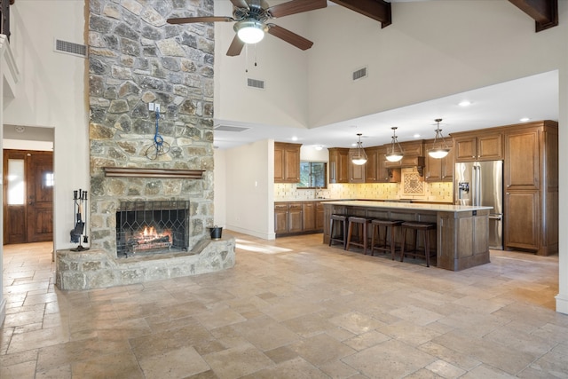 living area featuring visible vents, beamed ceiling, and stone tile flooring