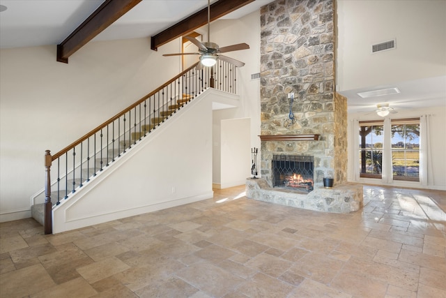 unfurnished living room with a stone fireplace, ceiling fan, beamed ceiling, and high vaulted ceiling