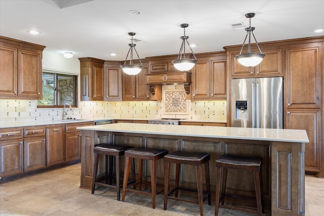 kitchen featuring a kitchen island, a breakfast bar area, appliances with stainless steel finishes, brown cabinetry, and a sink