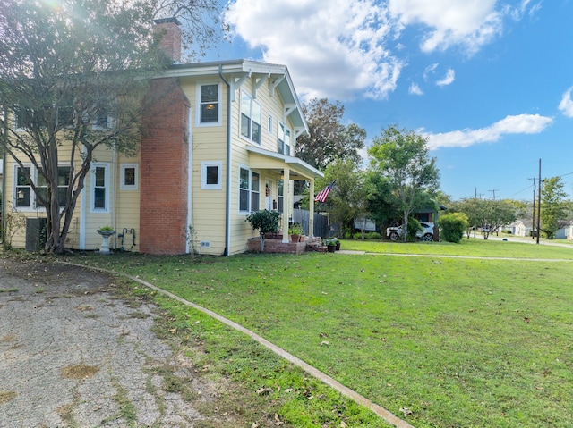 view of side of property featuring covered porch and a lawn