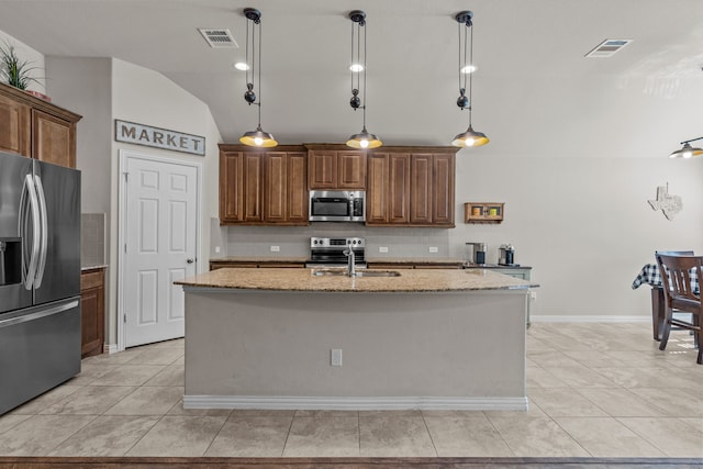 kitchen featuring lofted ceiling, an island with sink, decorative light fixtures, and appliances with stainless steel finishes