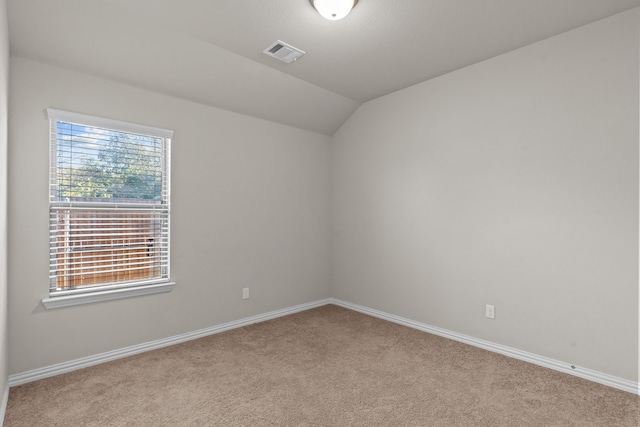 spare room with light colored carpet and vaulted ceiling