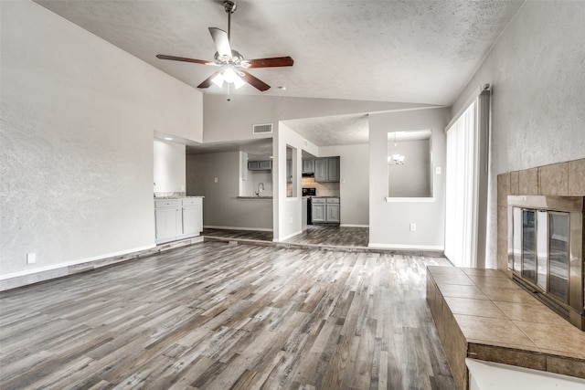 unfurnished living room with ceiling fan with notable chandelier, wood-type flooring, a textured ceiling, and high vaulted ceiling