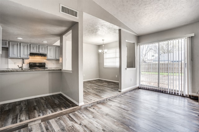 kitchen featuring gray cabinetry, backsplash, dark wood-type flooring, black stove, and a textured ceiling