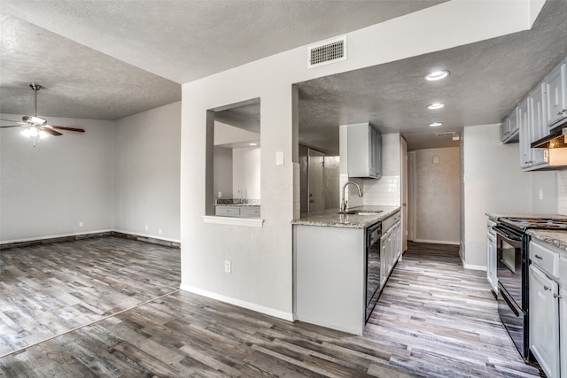 kitchen with hardwood / wood-style floors, black appliances, sink, ceiling fan, and a textured ceiling