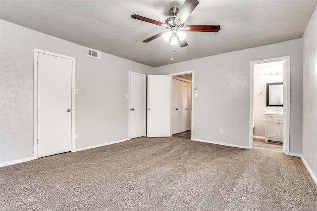 unfurnished bedroom with carpet flooring, ensuite bathroom, and ceiling fan