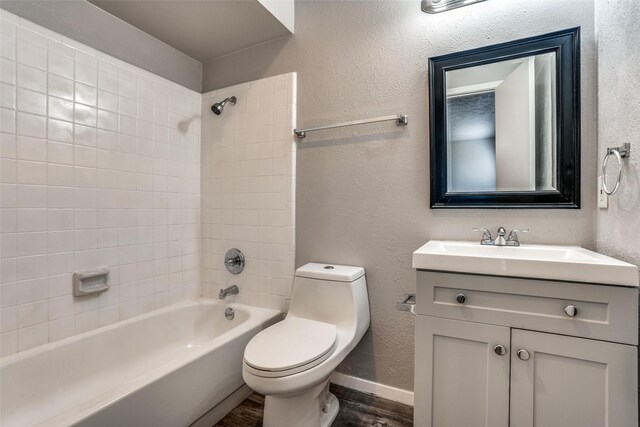 full bathroom featuring toilet, vanity, hardwood / wood-style floors, and tiled shower / bath