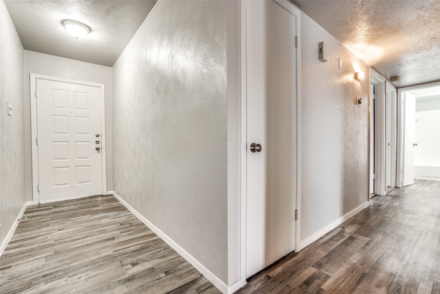 hall with wood-type flooring and a textured ceiling