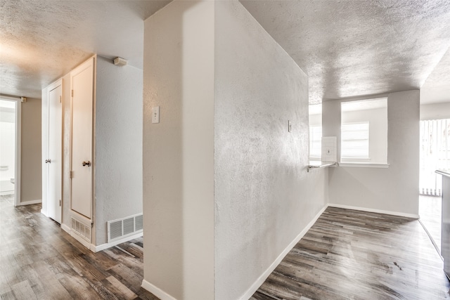 hall with dark hardwood / wood-style flooring and a textured ceiling