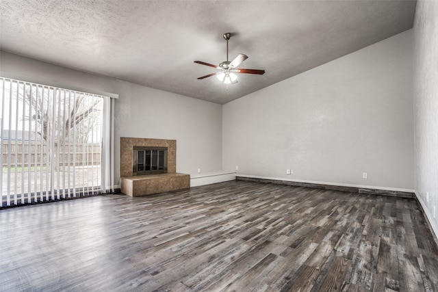 unfurnished living room with a textured ceiling, ceiling fan, dark hardwood / wood-style floors, lofted ceiling, and a tiled fireplace