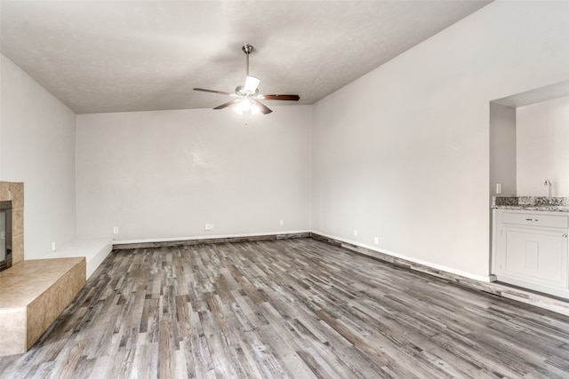 unfurnished living room with ceiling fan, light hardwood / wood-style floors, sink, and a tile fireplace