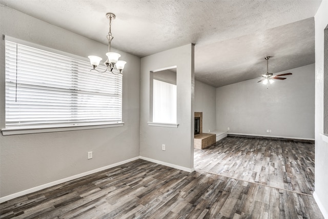 interior space with dark wood-type flooring, a textured ceiling, lofted ceiling, a fireplace, and ceiling fan with notable chandelier