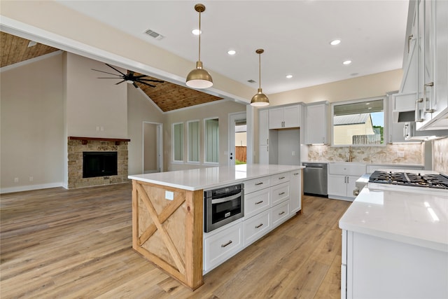 kitchen featuring white cabinetry, a center island, stainless steel appliances, vaulted ceiling with beams, and light hardwood / wood-style floors