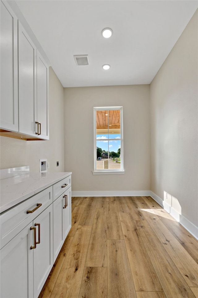 laundry room featuring cabinets, hookup for a washing machine, light hardwood / wood-style floors, and hookup for an electric dryer