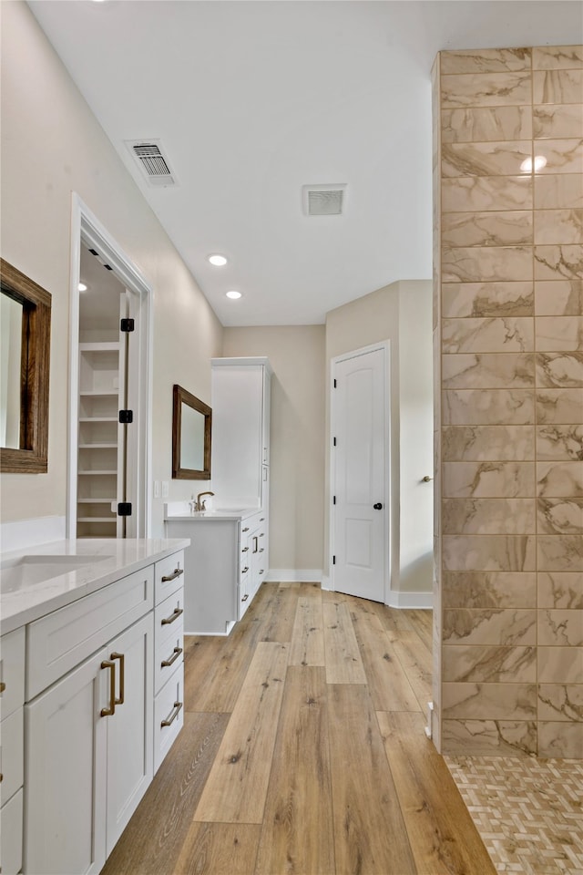 bathroom featuring hardwood / wood-style floors, vanity, and tiled shower