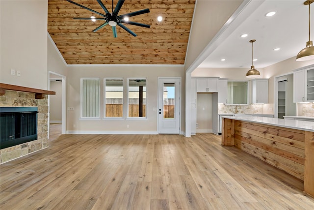 unfurnished living room with light wood-type flooring, ceiling fan, sink, high vaulted ceiling, and a fireplace