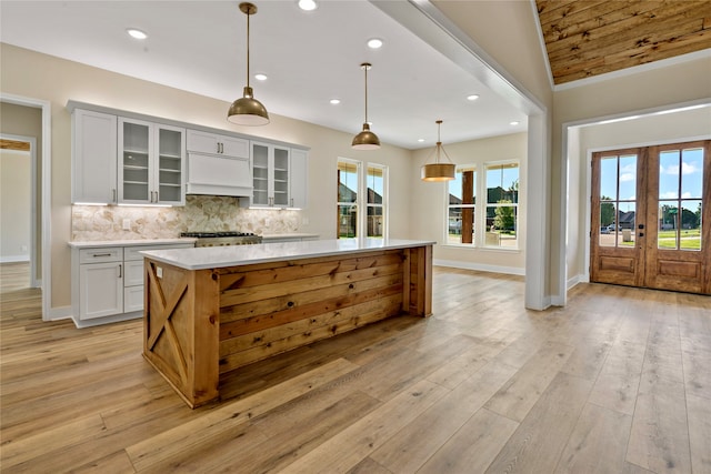 kitchen with white cabinets, a large island, hanging light fixtures, and french doors