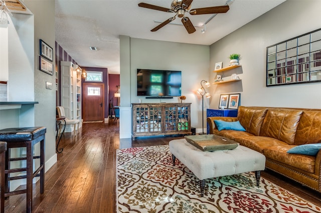 living room with a textured ceiling, ceiling fan, and dark hardwood / wood-style floors