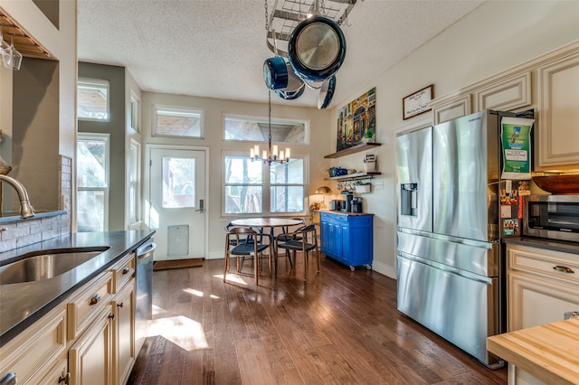 kitchen featuring sink, an inviting chandelier, dark hardwood / wood-style floors, cream cabinetry, and appliances with stainless steel finishes