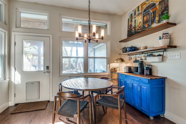 dining space with a textured ceiling, dark hardwood / wood-style floors, and a notable chandelier