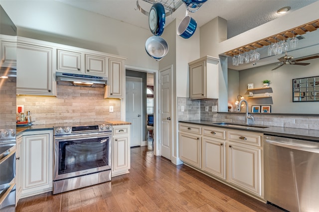 kitchen with sink, stainless steel appliances, cream cabinets, light hardwood / wood-style floors, and a textured ceiling