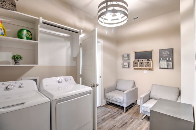 laundry room featuring a chandelier, light hardwood / wood-style flooring, and washer and clothes dryer