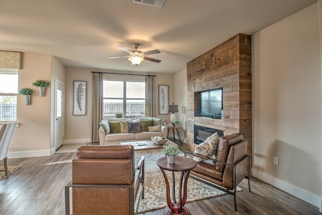 living room featuring ceiling fan, a large fireplace, and wood-type flooring