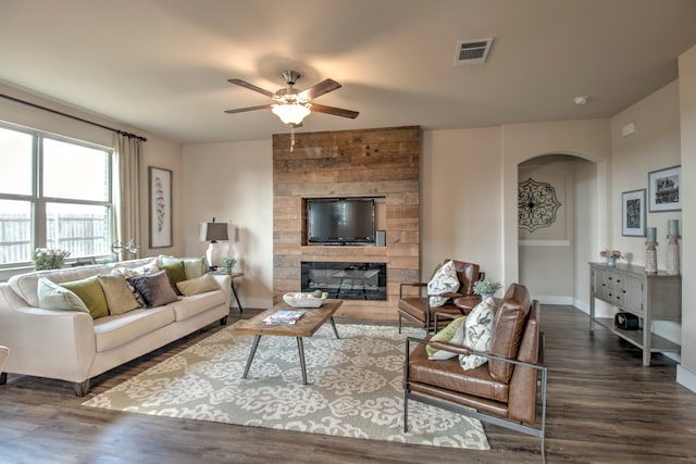 living room featuring ceiling fan, dark hardwood / wood-style flooring, and a fireplace