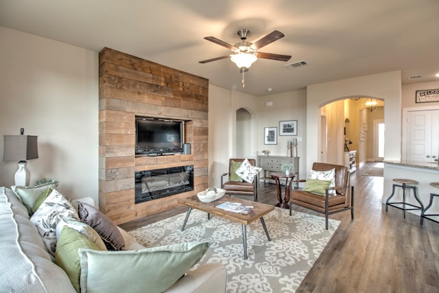 living room with hardwood / wood-style flooring, ceiling fan, and a fireplace