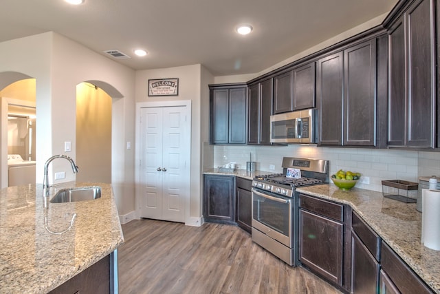 kitchen featuring light stone countertops, sink, stainless steel appliances, and hardwood / wood-style flooring