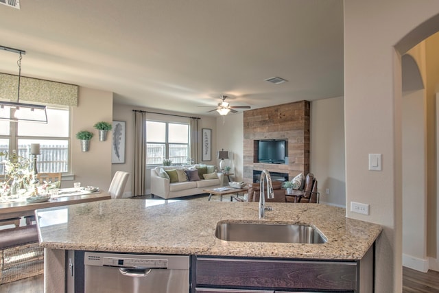 kitchen featuring light stone countertops, dark hardwood / wood-style flooring, stainless steel dishwasher, and sink