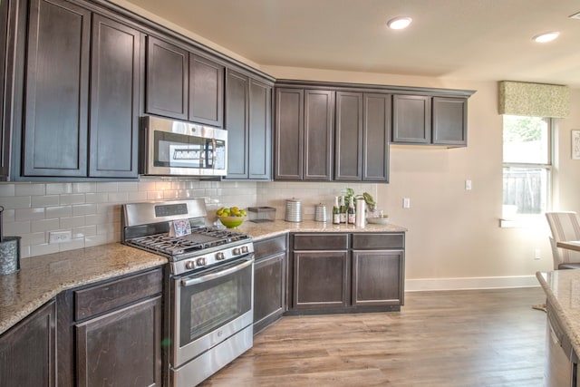 kitchen with light hardwood / wood-style flooring, decorative backsplash, light stone counters, dark brown cabinetry, and stainless steel appliances