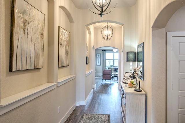 corridor featuring dark wood-type flooring and an inviting chandelier