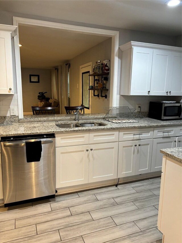 kitchen featuring light stone countertops, appliances with stainless steel finishes, sink, white cabinets, and light hardwood / wood-style floors