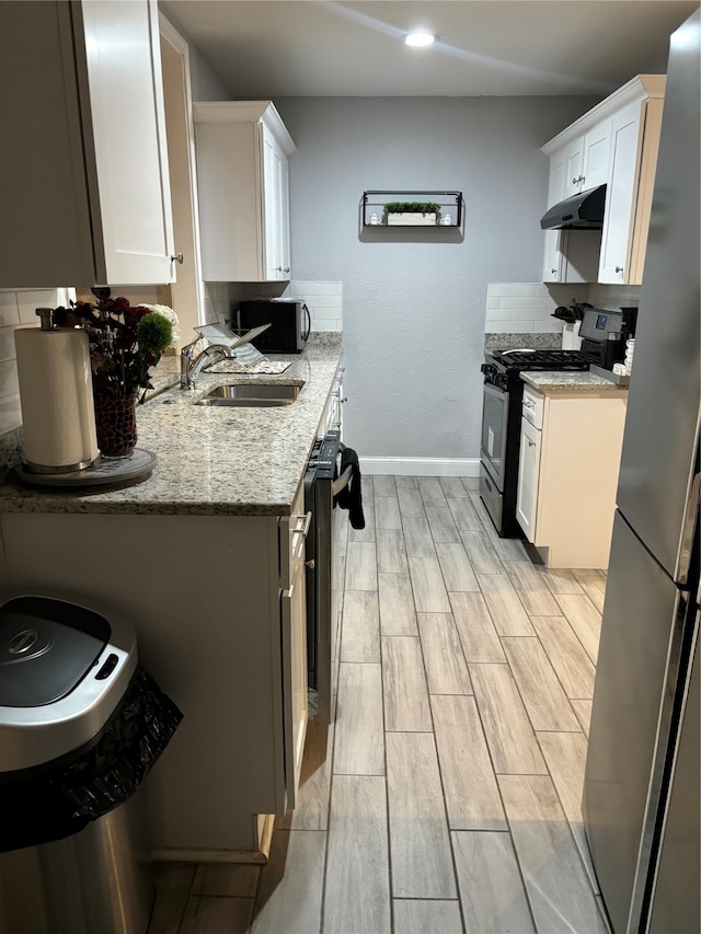 kitchen featuring white cabinetry, sink, stainless steel appliances, and light hardwood / wood-style flooring