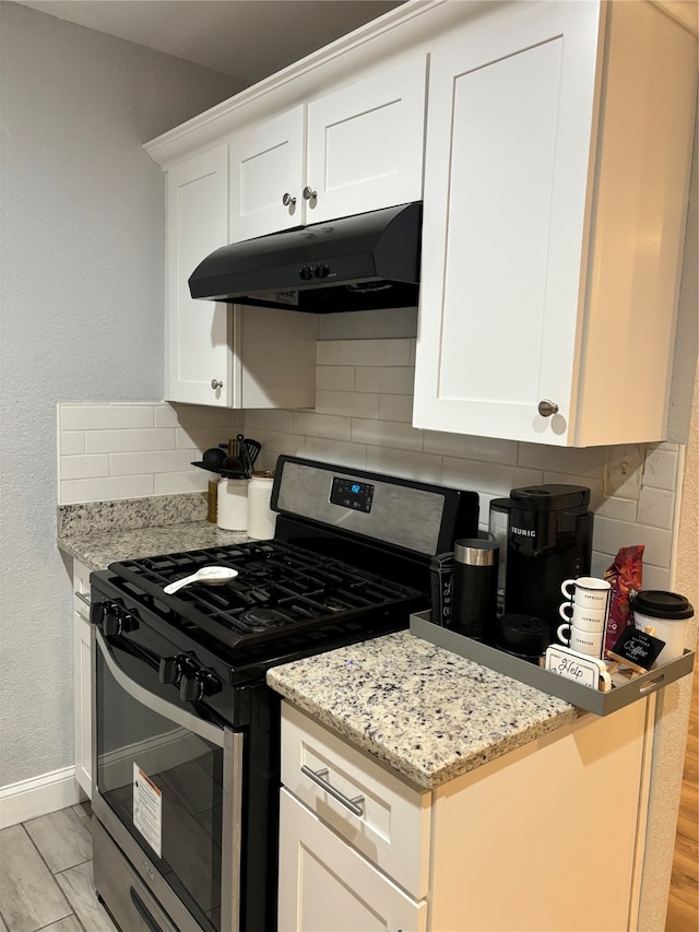 kitchen with gas stove, decorative backsplash, light hardwood / wood-style flooring, and white cabinets